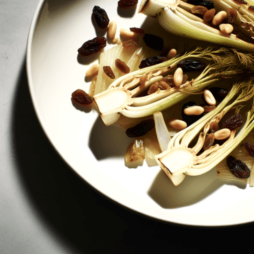 Suntuosos hinojos al horno con piñones y pasas, realzados por el sabor del Parmesano y la crujiente textura de las almendras. Un acompañamiento ligero y sabroso con aromas mediterráneos.