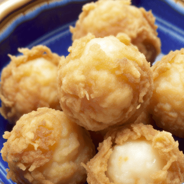 Deliciosas croquetas de bacalao tradicionales y crujientes, hechas con bacalao remojado, patatas, huevos, perejil y ajo. Sirva crujientes y doradas después de una delicada fritura en aceite de oliva. ¡Un plato irresistible que conquistará a sus invitados!